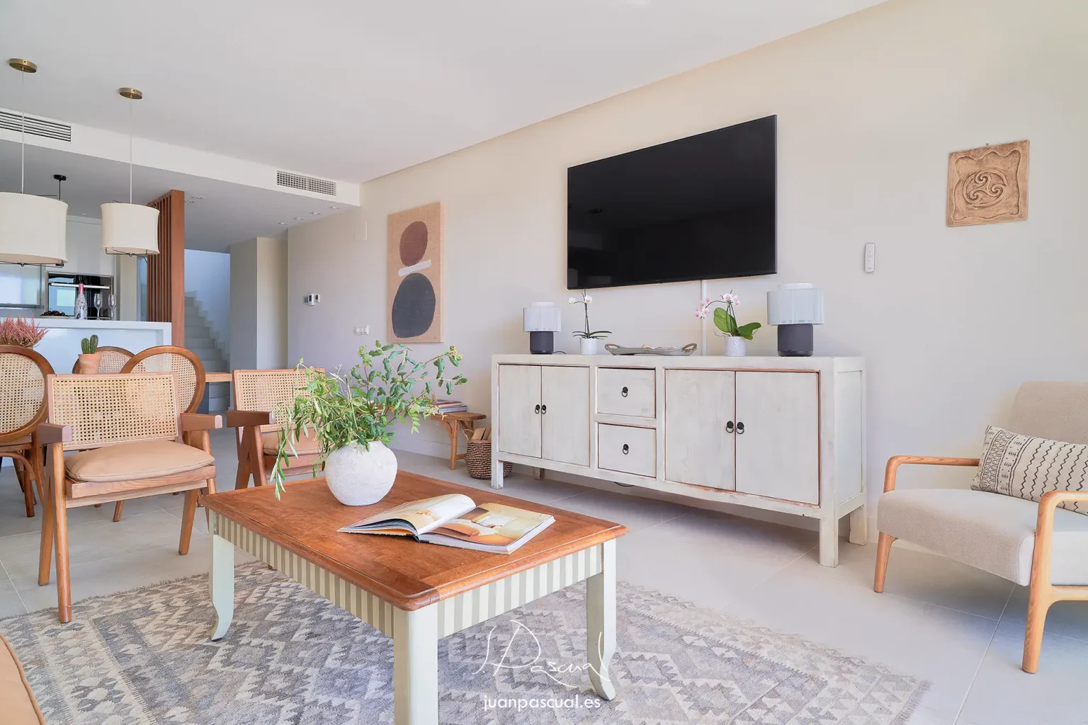 Fotografía de apartamento en Marbella, del fotógrafo inmobiliario Juan Pascual. Salón y cocina con escalera de subida a planta superior al fondo. Mobiliario estilo mediterráneo clásico.